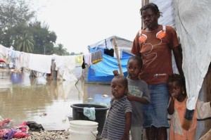 Velia Dorce with her children stand outside their tent flooded by Hurricane Tomas. ACT Alliance members are supporting people during this new emergency. Arne Grieg Riisnaes/NCA/ACT