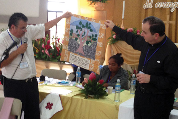 Mission pastor Rev. Edmundo Retana of San Jose, Costa Rica, presents a handcrafted wall-hanging on a Biblical theme as a gift to President Bugbee for LCC's office in Winnipeg.