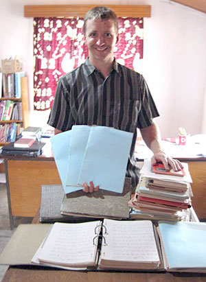 Rev. Kuhn poses with the rediscovered drafts of Scripture in the Nizaa language.