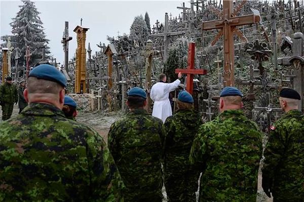 The Air Task Force Lithuania chaplain [Rev. Gerson Flor] blesses the cross during the dedication ceremony of Canada's cross for NATO Baltic Air Policing Block 36 on November 30, 2014 at the Hill of Crosses in Šiauliai, Lithuania. (Photo: Photo: Air Task Force - OP Reassurance, DND)