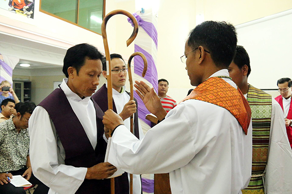 The newly ordained pastors are presented with shepherds' crooks by ELCC President Vannarith Chhim.